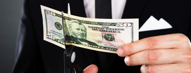 Businessman Cutting Dollar Bill With Scissors